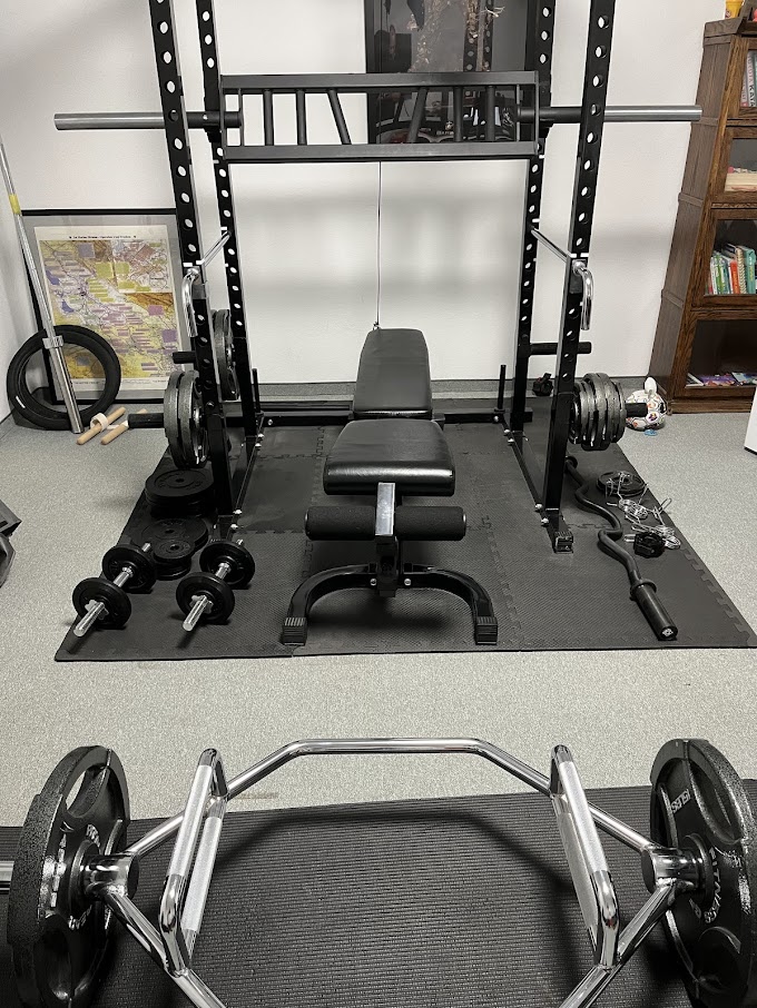 dumbbells, bench, multi grip bar, power rack in a home gym setting