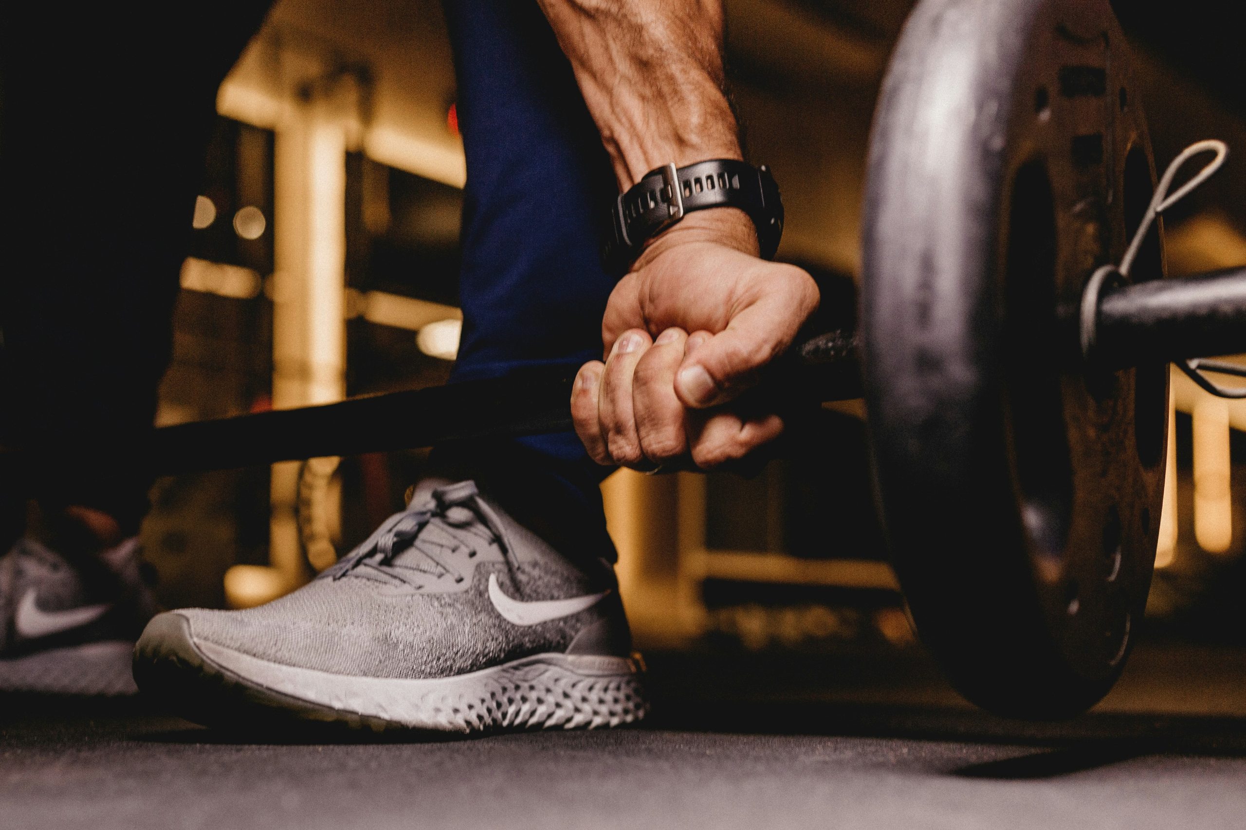 A man lifting a barbell in a home gym, demonstrating an effective workout split for strength training.