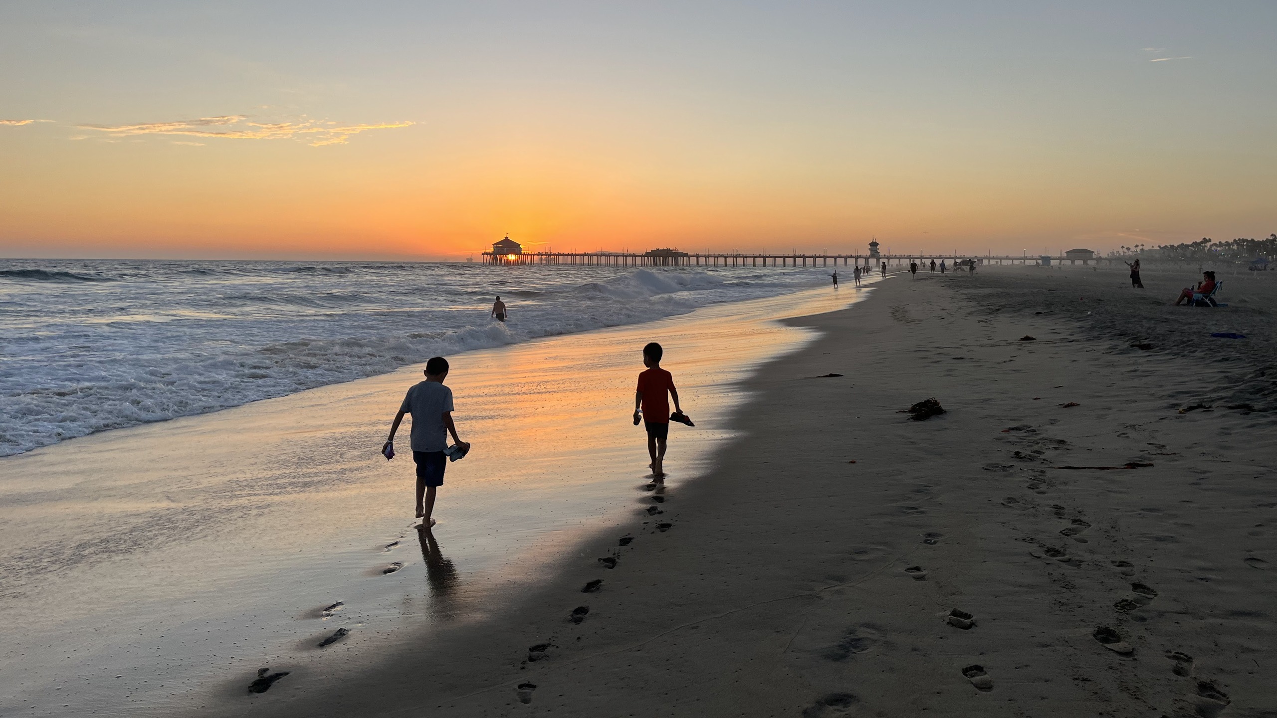 Two young boys walking along a beach at sunset toward a pier, reflecting the balance of family, fitness and finance